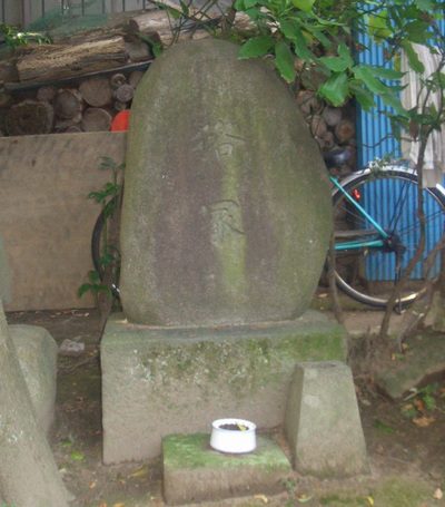 寺の境内に立つ、苔むした細長い自然石の塚