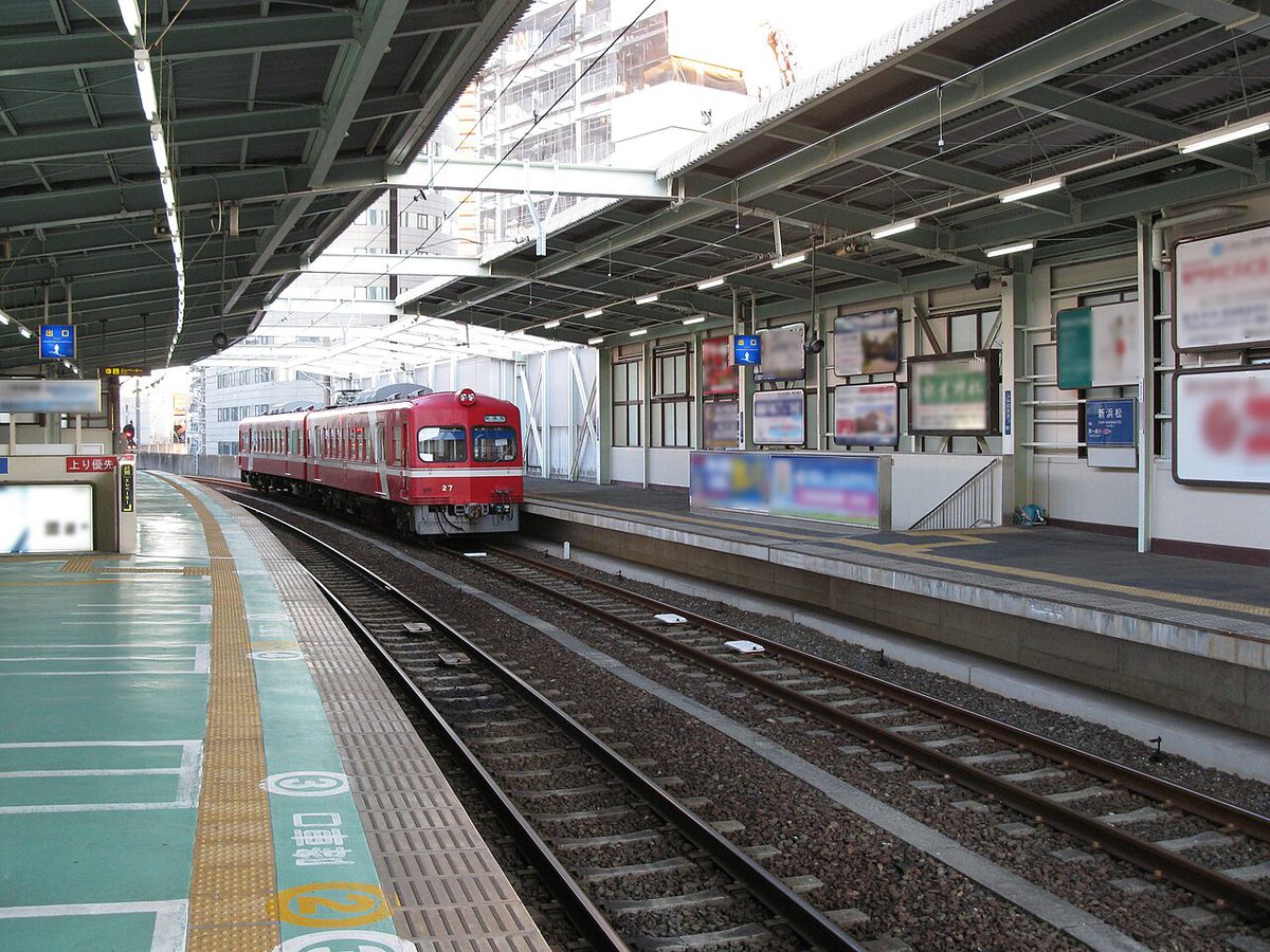 遠州鉄道の新浜松駅のホーム。赤い電車が止まり、天井の低い高架の駅舎が続く