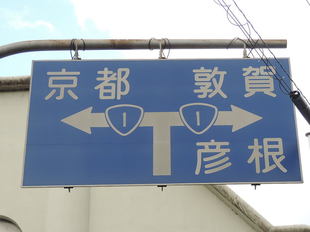 青地に白い文字で「京都」「敦賀」「彦根」と行き先を示す古い型の道路の案内標識