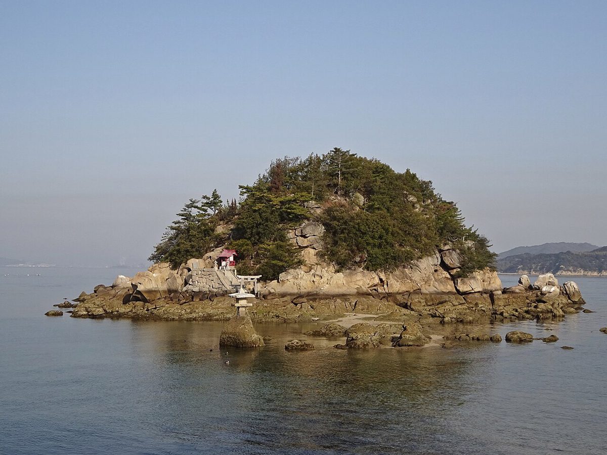 静かな海に浮かぶ、松の茂る岩の小島。岩の上に小さな赤い祠が見える