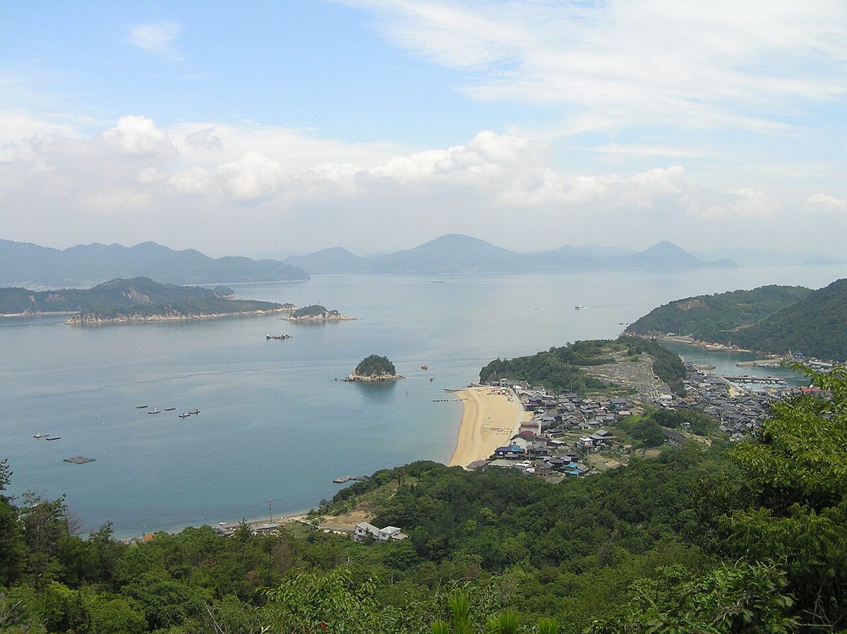 高台から見下ろした白石島。緑の山の向こうに砂浜と集落、穏やかな瀬戸内海に島々が浮かぶ