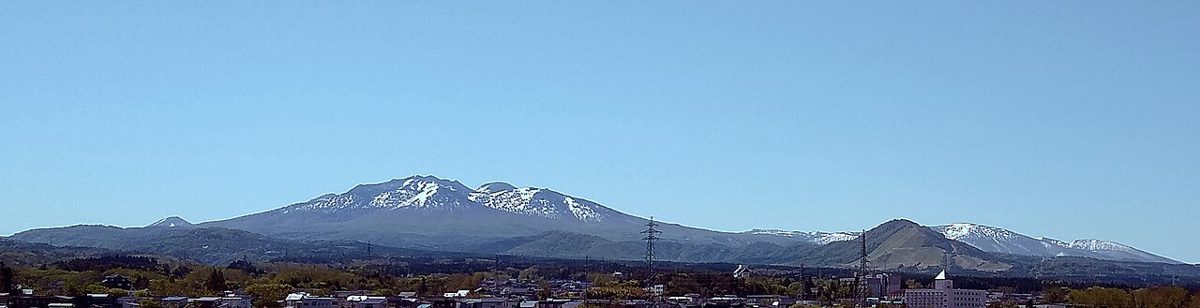 街の向こうに連なる雪の残る八甲田の山々